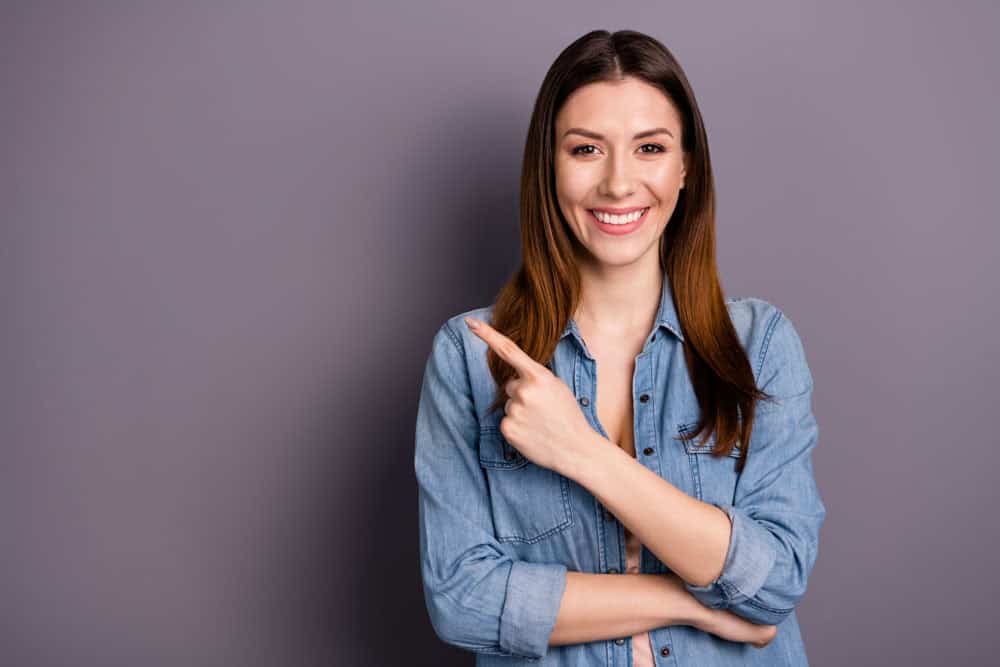 Woman pointing to her smile after cosmetic dentistry treatment in Colorado Springs, CO