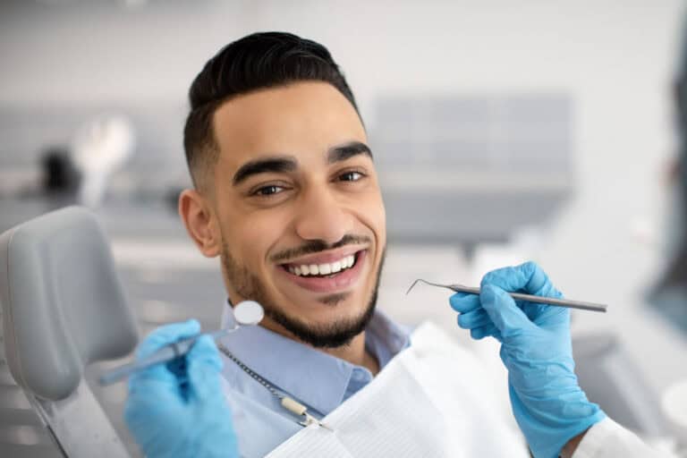 Man smiling in dental chair after receiving dental crown at restorative dentist in Colorado Springs