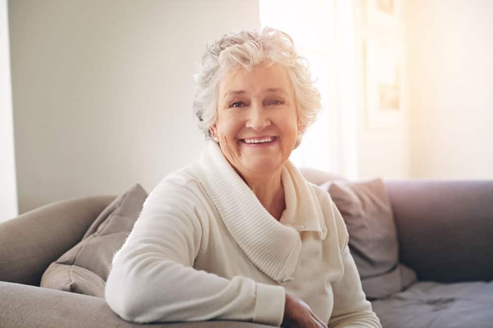 Senior woman smiling confidently at home after dental implant procedure in Colorado Springs, CO