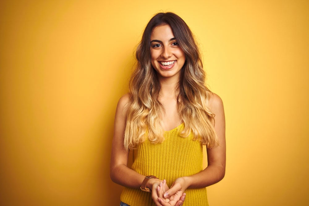 Young woman with fingers crossed hoping to qualify as ideal dental implant candidate in Colorado Springs