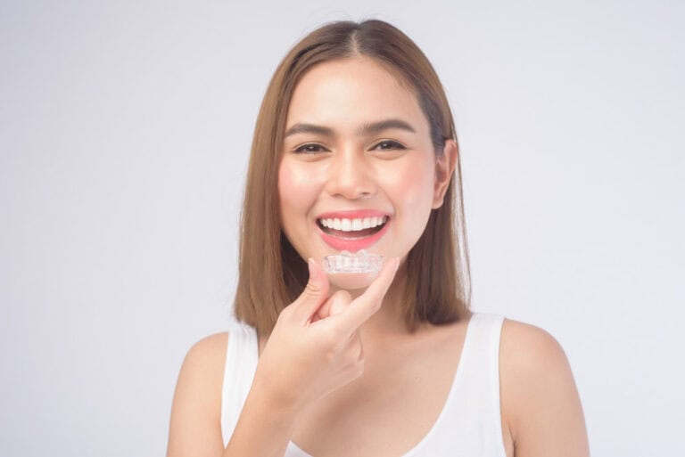 Woman holding Invisalign clear aligners for orthodontic treatment in Colorado Springs, CO