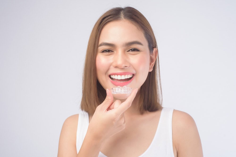 Woman holding Invisalign clear aligners for orthodontic treatment in Colorado Springs, CO