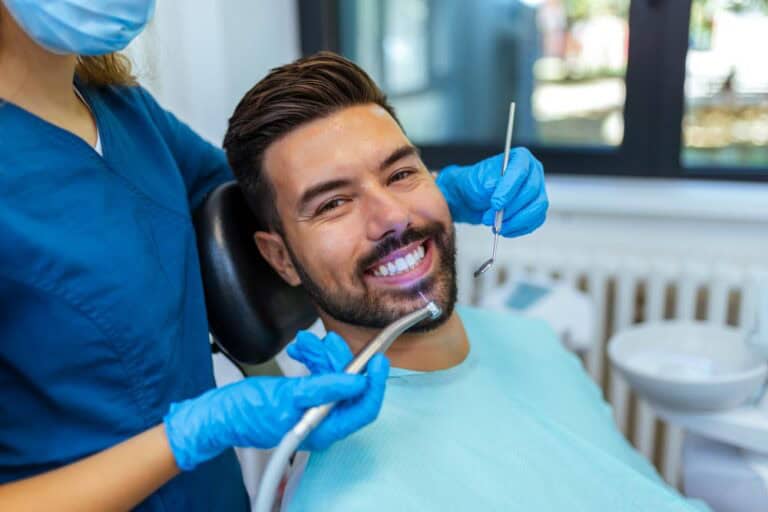 Female dentist placing dental crown on male patient following root canal recovery