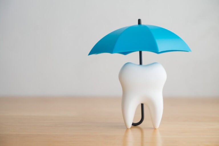 Tooth model protected under umbrella symbolizing root canal recovery care in Colorado Springs