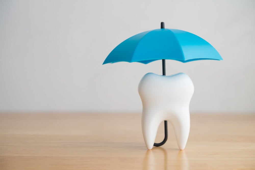 Tooth model protected under umbrella symbolizing root canal recovery care in Colorado Springs