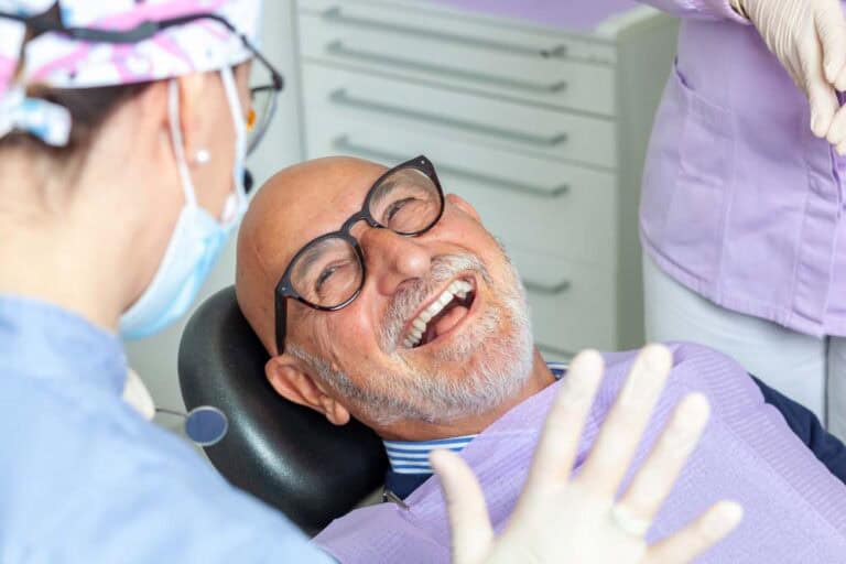 Senior male patient laughing comfortably in dental chair after successful root canal treatment