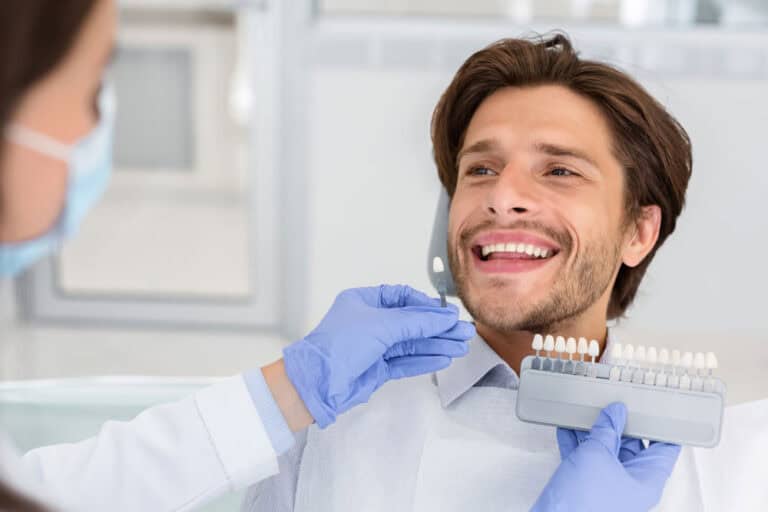 Dentist checking tooth enamel color shade for professional teeth whitening treatment in Colorado Springs