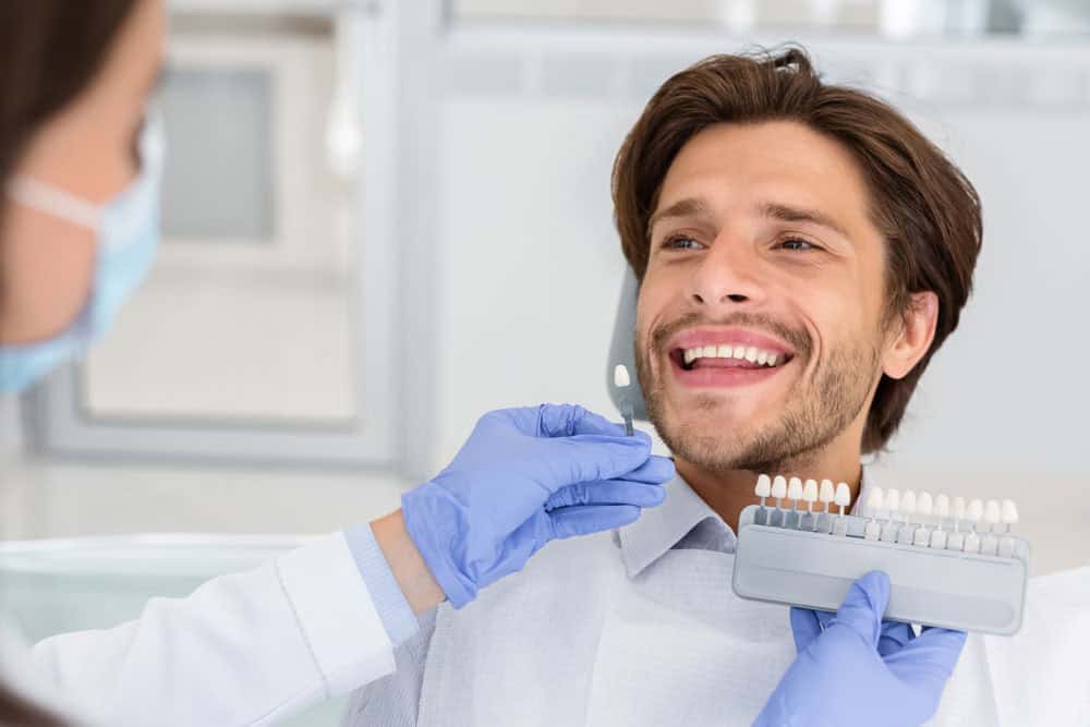 Dentist checking tooth enamel color shade for professional teeth whitening treatment in Colorado Springs