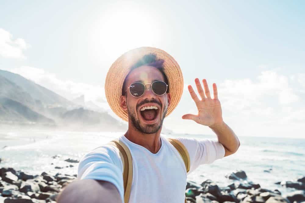 Young man taking outdoor selfie with confident smile after dental crown procedure in Colorado Springs